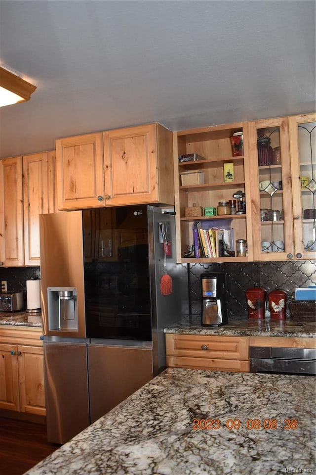 kitchen featuring dark stone counters, glass insert cabinets, stainless steel fridge, and oven