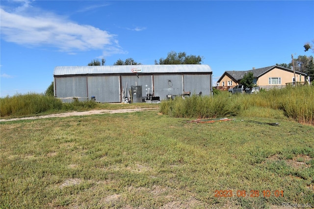 back of property featuring a yard, an outdoor structure, and an outbuilding