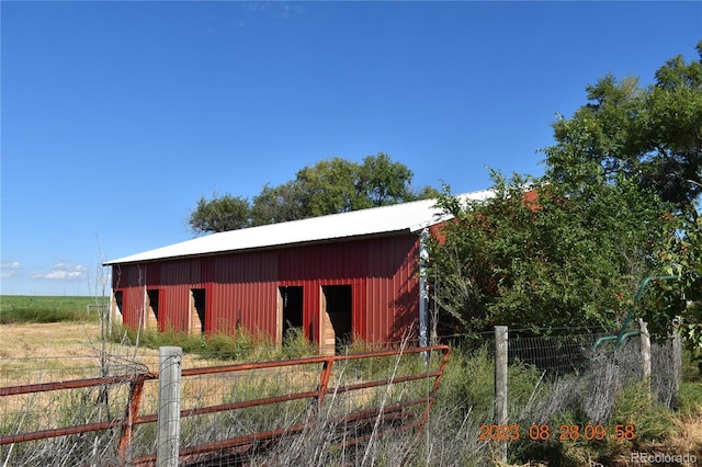 view of outbuilding featuring a rural view, an outdoor structure, and fence