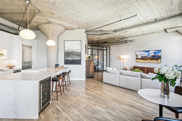 kitchen featuring stainless steel built in refrigerator, white cabinets, wine cooler, pendant lighting, and light hardwood / wood-style floors