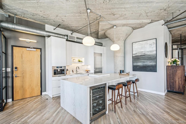 kitchen with light hardwood / wood-style floors, white cabinetry, wine cooler, and decorative light fixtures