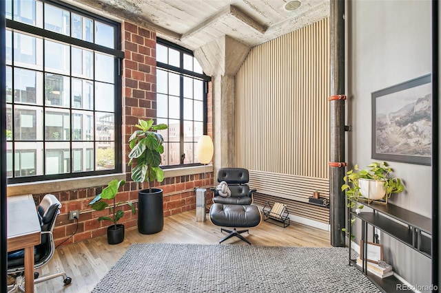 sitting room with brick wall and hardwood / wood-style floors