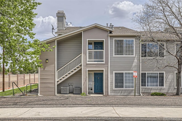 rear view of property with fence, a chimney, and central AC