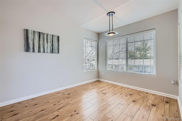 spare room with baseboards and wood finished floors
