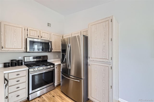 kitchen featuring stainless steel appliances, light countertops, light wood-style floors, and light brown cabinets