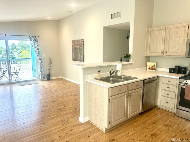 kitchen featuring stainless steel appliances, a sink, light countertops, and light wood-style floors