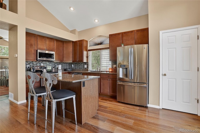 18153 E Amherst Dr, Aurora, CO 80013 - kitchen with stainless steel appliances, a kitchen bar, light wood-type flooring, a kitchen island, and backsplash