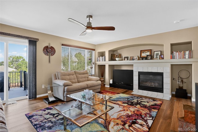 18153 E Amherst Dr, Aurora, CO 80013 - living area featuring ceiling fan, built in shelves, wood finished floors, and a tiled fireplace