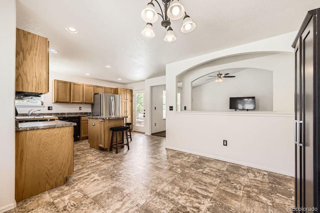 5770 Waverley Ave, Firestone, CO 80504 - kitchen with freestanding refrigerator, dark countertops, a ceiling fan, a breakfast bar, and a kitchen island