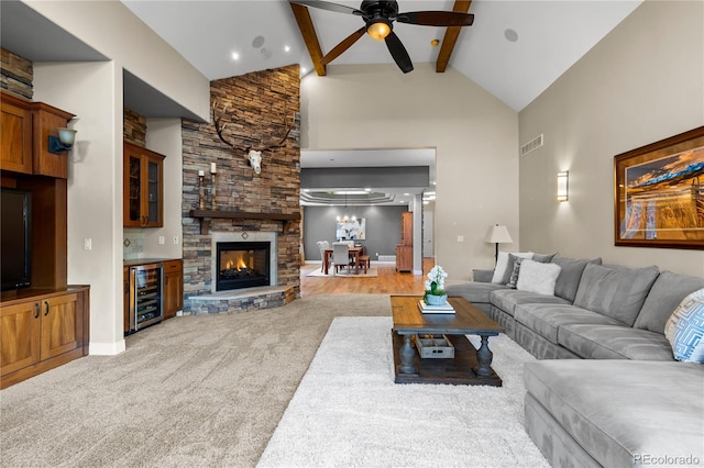 living room with beam ceiling, high vaulted ceiling, ceiling fan, beverage cooler, and light colored carpet