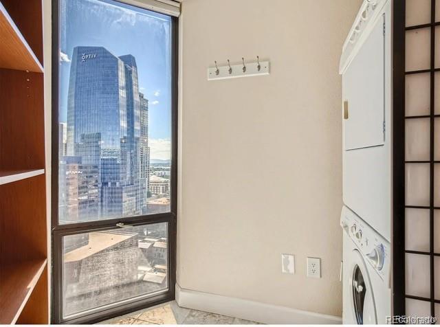 laundry room with stacked washer and clothes dryer and a wealth of natural light