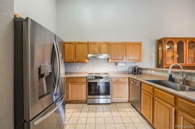 kitchen with under cabinet range hood, light countertops, light tile patterned floors, appliances with stainless steel finishes, and a sink