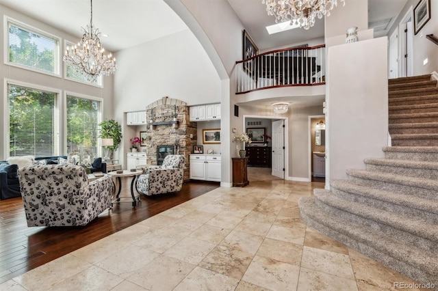 interior space with a stone fireplace, a towering ceiling, and light hardwood / wood-style flooring