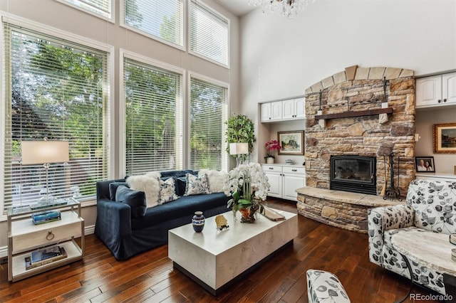 living room with a healthy amount of sunlight, a fireplace, a towering ceiling, and dark hardwood / wood-style floors