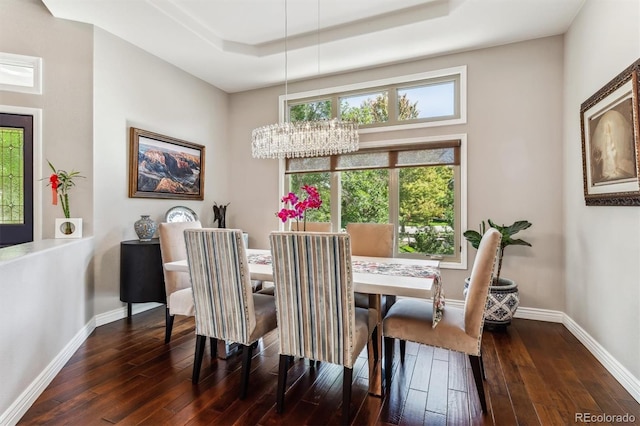 dining area featuring a notable chandelier, a raised ceiling, and dark hardwood / wood-style flooring