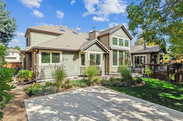 back of property with a yard and a wooden deck