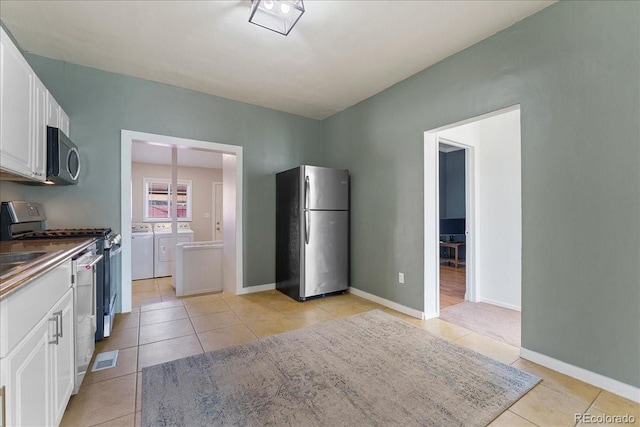 3300 W 2nd Ave, Denver, CO 80219 - kitchen featuring stainless steel appliances, independent washer and dryer, light tile patterned floors, and white cabinets
