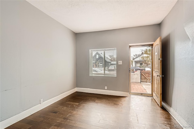 spare room with a textured ceiling and dark wood-type flooring