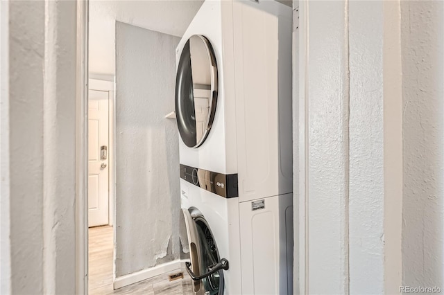 laundry area featuring stacked washing maching and dryer and light hardwood / wood-style floors