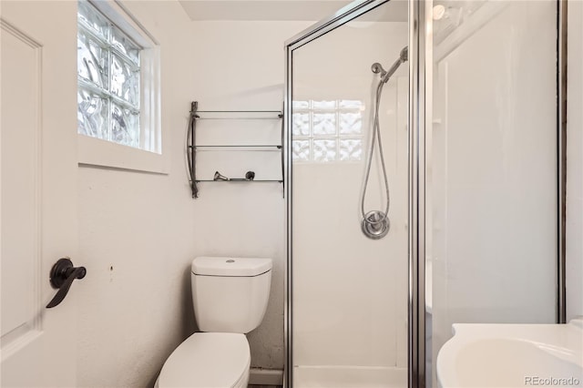 bathroom featuring toilet and a shower with shower door