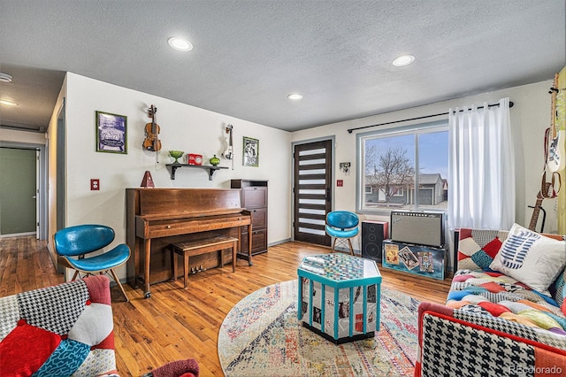 living room with a textured ceiling, baseboards, wood finished floors, and recessed lighting