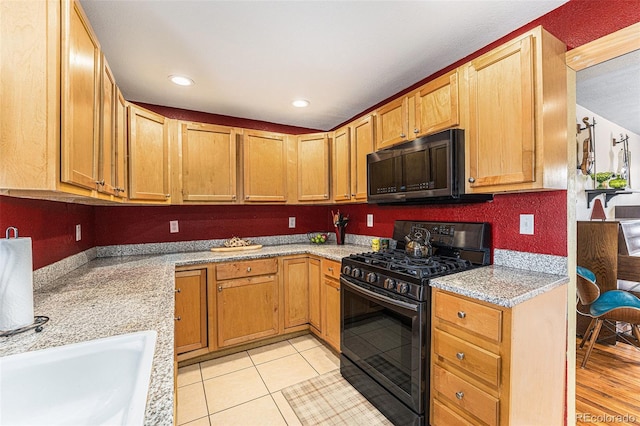 kitchen with light tile patterned floors, recessed lighting, a sink, stainless steel range with gas cooktop, and light stone countertops