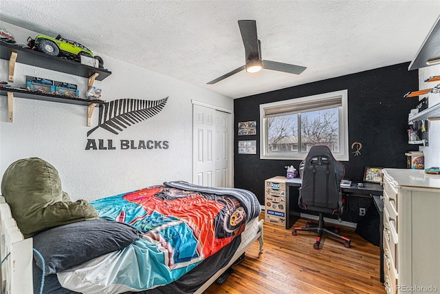 bedroom with a closet, a textured wall, a ceiling fan, a textured ceiling, and wood finished floors