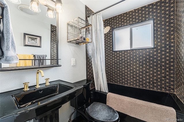 bathroom featuring a textured wall and a sink