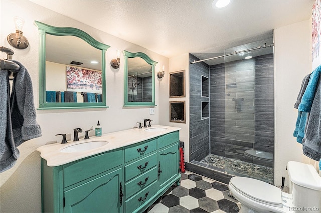 full bathroom featuring toilet, double vanity, a sink, and tiled shower