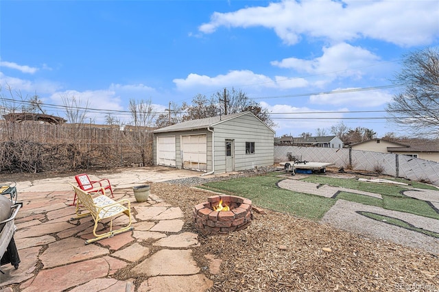 view of yard with a garage, an outdoor fire pit, an outbuilding, fence, and a patio area