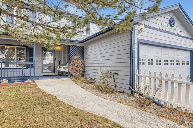 entrance to property featuring a garage, a yard, and covered porch