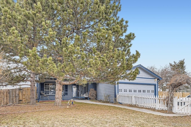 view of property hidden behind natural elements featuring a garage and a front lawn