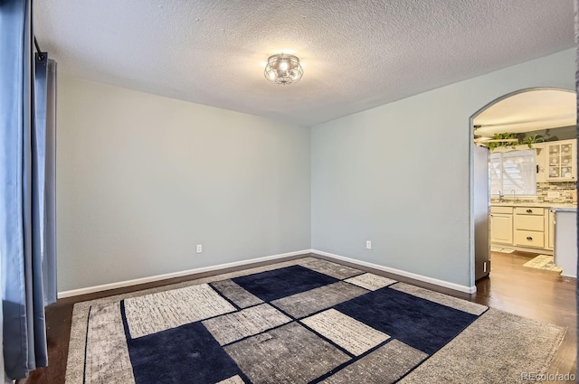 unfurnished room with dark hardwood / wood-style floors, sink, and a textured ceiling