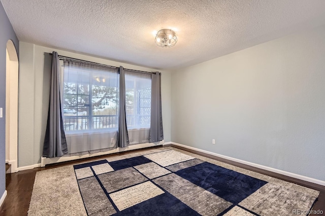 spare room featuring dark wood-type flooring, a baseboard radiator, and a textured ceiling