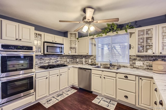 kitchen featuring sink, dark wood-type flooring, appliances with stainless steel finishes, backsplash, and light stone countertops