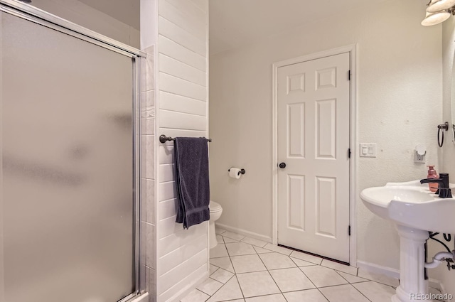 bathroom featuring toilet, an enclosed shower, and tile patterned flooring