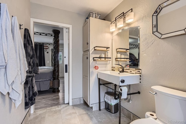 bathroom with toilet, sink, and decorative backsplash