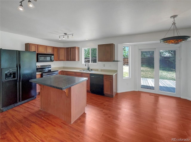 12550 Eastlake Dr, Thornton, CO 80241 - kitchen with black appliances, a sink, wood finished floors, a kitchen island, and a breakfast bar