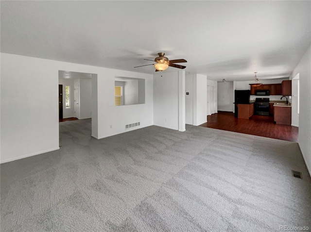 12550 Eastlake Dr, Thornton, CO 80241 - unfurnished living room featuring a sink, dark colored carpet, ceiling fan, and baseboards