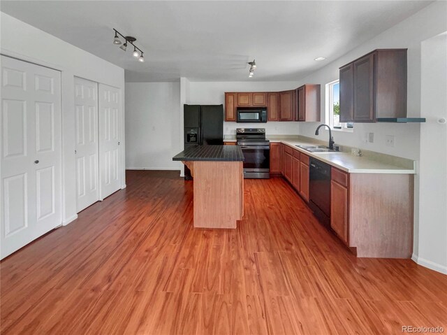 12550 Eastlake Dr, Thornton, CO 80241 - kitchen with black appliances, a sink, a kitchen island, light wood-style floors, and baseboards
