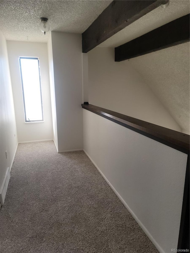 interior space featuring vaulted ceiling with beams, carpet floors, and a textured ceiling