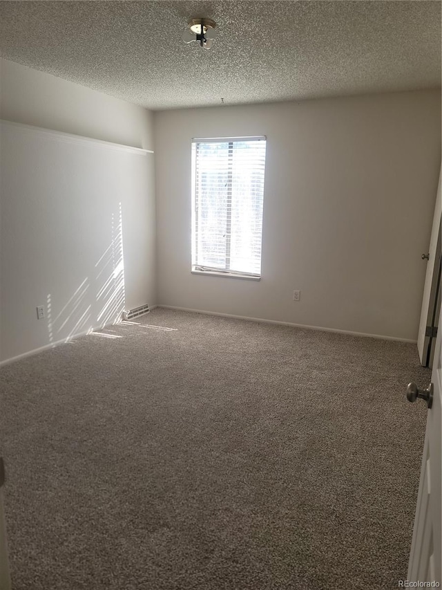 carpeted empty room with a textured ceiling