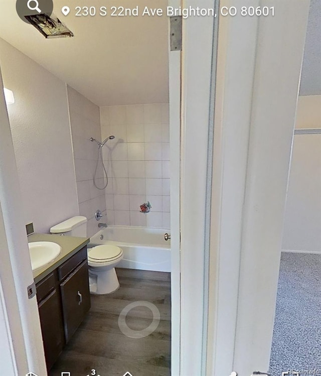 full bathroom featuring vanity, wood-type flooring, tiled shower / bath, and toilet