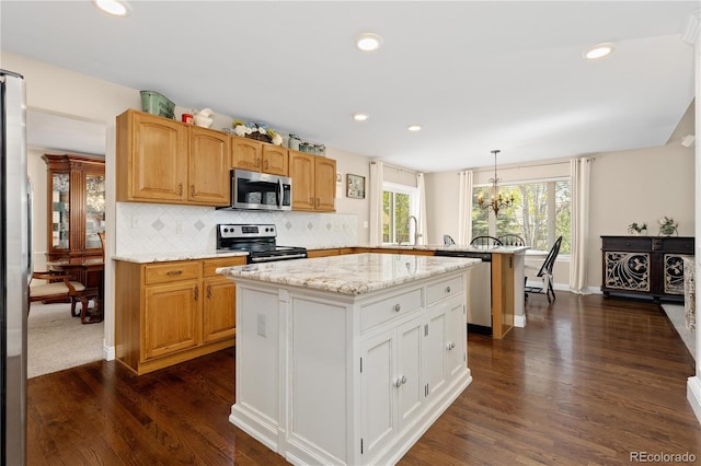 1774 Spring Water Pl, Highlands Ranch, CO 80129 - kitchen with appliances with stainless steel finishes, a peninsula, dark wood finished floors, a chandelier, and tasteful backsplash