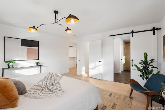 bedroom with wood-type flooring and a barn door