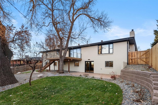 back of property featuring a wooden deck and a yard