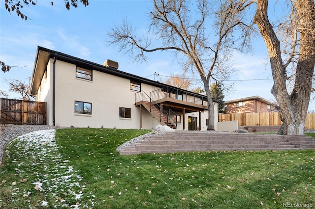 rear view of house featuring a wooden deck and a yard