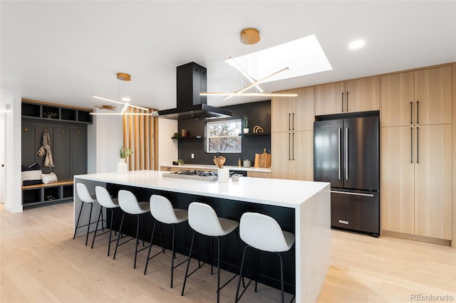 kitchen featuring island range hood, a center island with sink, decorative light fixtures, and appliances with stainless steel finishes