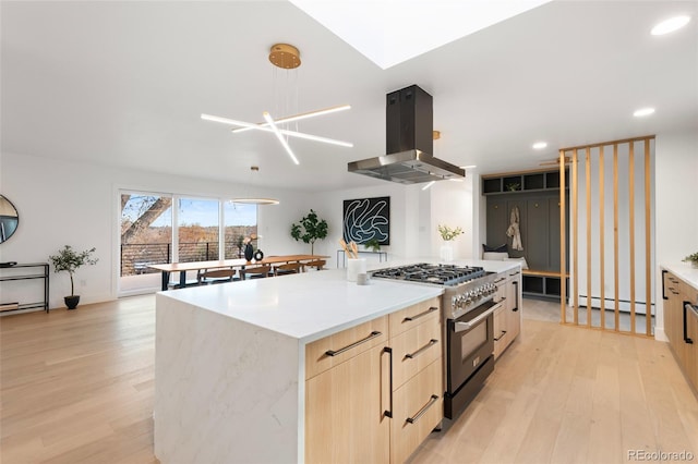 kitchen with island exhaust hood, high end stainless steel range, a kitchen island, and light hardwood / wood-style floors