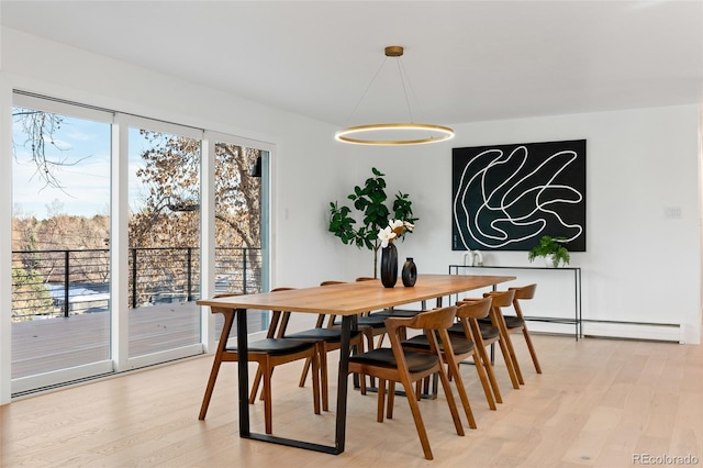 dining space with light hardwood / wood-style flooring and a baseboard heating unit